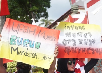 ASPIRASI: Banner bermuatan keluh kesah buruh disunggi tinggi-tinggi oleh peserta aksi buruh menolak kenaikan UMK sebesar 0,06 persen, belum lama ini. (Adhik Kurniawan / Lingkarjateng.id)
