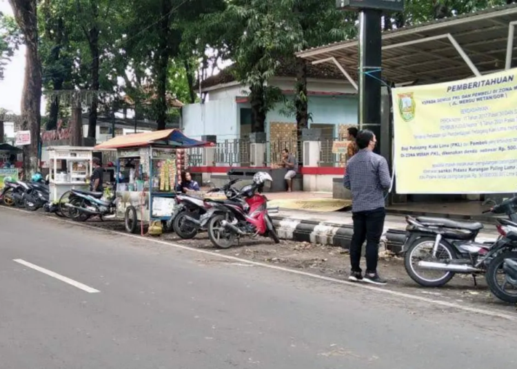 ANTARA/LINGKAR JATENG
ILUSTRASI: Seorang warga tengah membaca spanduk bertuliskan soal Perda nomor 11/2017 tentang Penataan dan Pemberdayaan PKL.