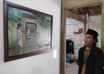 INDAH: Pino seniman Lasem menunjukan hasil karya lukisnya yang dipajang di pameran Cerita Nyah Lasem, kemarin. (R. Teguh Wibowo / Lingkarjateng.id)