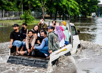 TETAP CERIA: Beberapa pekerja pabrik berangkat kerja dengan menggunakan mobil pick up, karena motor mogok tergenang air di kawasan industri Pelabuhan Tanjung Emas. (Dinda Rahmasari / Lingkarjateng.id)