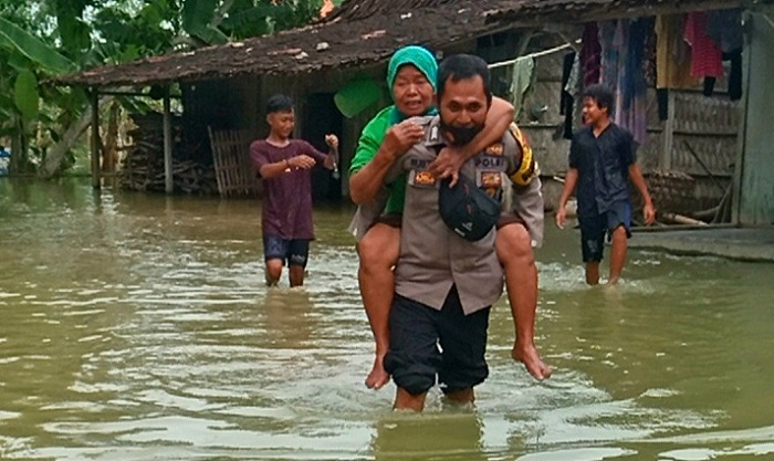 EVAKUASI: Bhabinkamtibmas Desa Lemahputih, saat membantu evakuasi warga yang rumahnya mengalami kebanjiran. (Muhamad Ansori / Lingkarjateng.id)