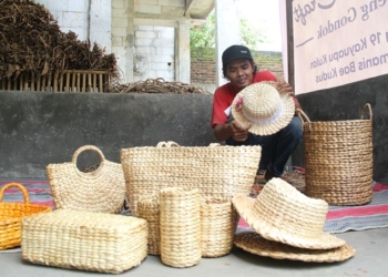 TERAMPIL: Ali Wahyudi sedang mengecek produk kerajinan eceng gondok buatannya supaya tidak ada kerusakan sebelum dijual kepada pembeli. (Nisa Hafizhotus Syarifa/Lingkarjateng.id)