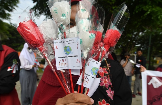 MEMPERINGATI: Seorang mahasiswa membawa bunga kertas untuk dibagikan kepada pengguna jalan saat memperingati Hari AIDS Sedunia di Palu, Rabu (1/12). (Antara / Lingkarjateng.id)