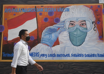 ILUSTRASI: Warga melintas di dekat mural bertema Covid-19. (Istimewa / Lingkarjateng.id)