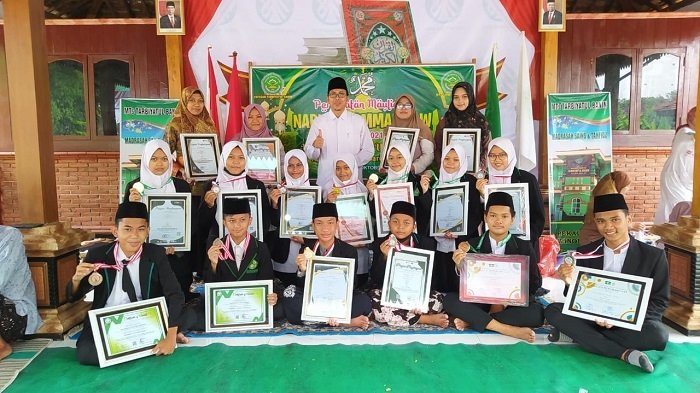 BANGGA: Kepala MTs Tarbiyatul Banin Winong Yusuf Hasyim yang juga Ketua PCNU Pati (tengah berpeci hitam, Red) berfoto bersama anak didiknya yang berhasil meraih medali dalam ajang OSPN 2021. (Nailin RA / Lingkarjateng.id)