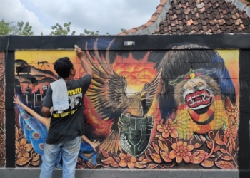 MELUKIS: Salah satu kontestan tengah mengikuti Lomba Mural Tingkat Nasional Di Desa Bradag, Kecamatan Ngawen, Blora. (Humas Blora/Lingkarjateng.id)