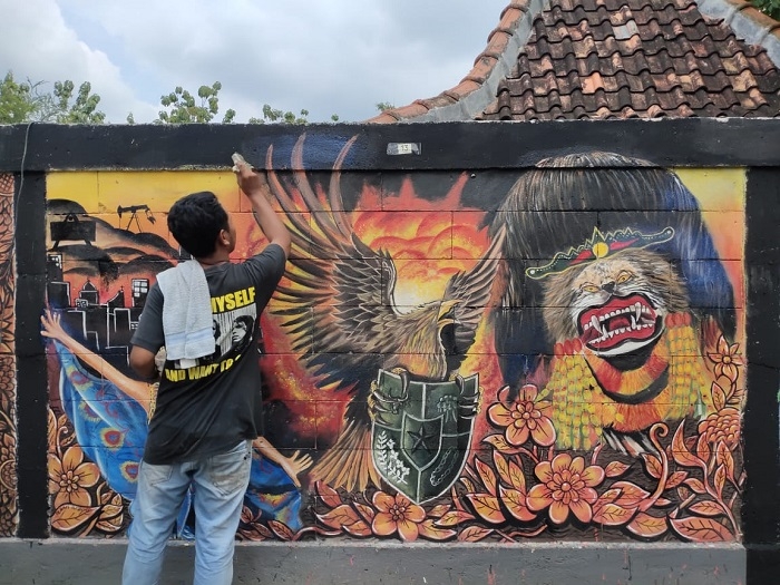 MELUKIS: Salah satu kontestan tengah mengikuti Lomba Mural Tingkat Nasional Di Desa Bradag, Kecamatan Ngawen, Blora. (Humas Blora/Lingkarjateng.id)