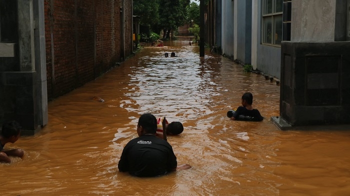 TERGENANG: Sejumlah masyarakat Desa Tegalsambi, Tahunan, Jepara sedang berjalan melewati banjir yang menggenangi desa tersebut, Sabtu (11/12). (Istimewa/Lingkarjateng.id)