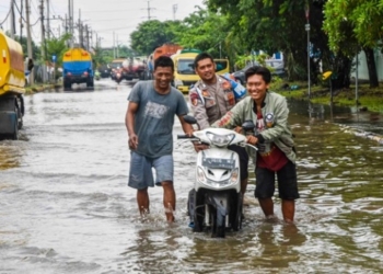 BANJIR: Beberapa orang sedang mendorong motor melewati genangan banjir di salah satu wilayah di Kota Semarang beberapa waktu lalu. (Dinda Rahmasari/Lingkarjateng.id)