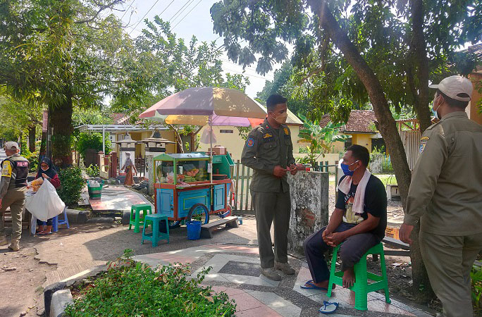 STERILISASI: Regu unit Satuan Polisi Pamong Praja (Satpol PP) Kabupaten Demak menegur Pedagang Kaki Lima (PKL) di pinggir Jl. Bhayangkara Baru, Demak, Senin (24/1). (M. Elang Ade Iswara/Lingkarjateng.id)