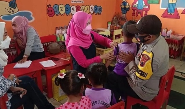 MONITORING: Bhabinkamtibmas Desa Mojosimo, Polsek Gajah saat memantau jalannya kegiatan vaksinasi anak usia 6-11 tahun di TK Cempaka Sari, Demak, Sabtu (15/1). (M. Elang Ade Iswara/Lingkarjateng.id)