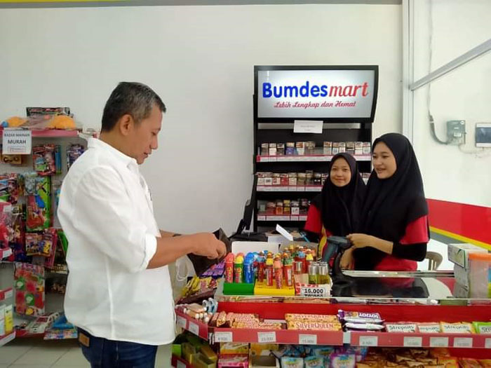 TRANSAKSI: Junarso, Wakil Ketua DPRD Jepara berbelanja produk di Bumdesmart yang dikelola desa. (Muslichul Basid/Lingkarjateng.id)