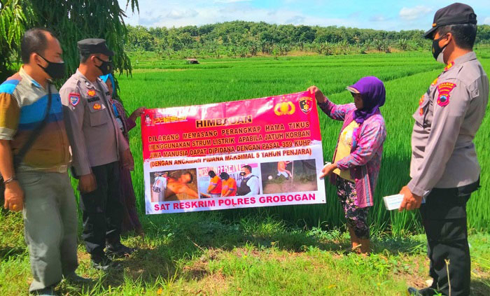 SOSIALISASI: Petugas dari kepolisian Polres Grobogan sedang memasang banner imbuan larangan menggunakan listrik untuk jebakan tikus di wilayah setempat, Senin (10/1). (Muhamad Andori/Lingkarjateng.id)