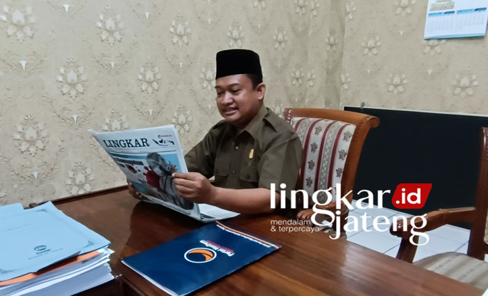 FOKUS: Nur Hidayat, Ketua komisi C DPRD Jepara membaca Koran Lingkar. (Muslichul Basid/Lingkarjateng.id)