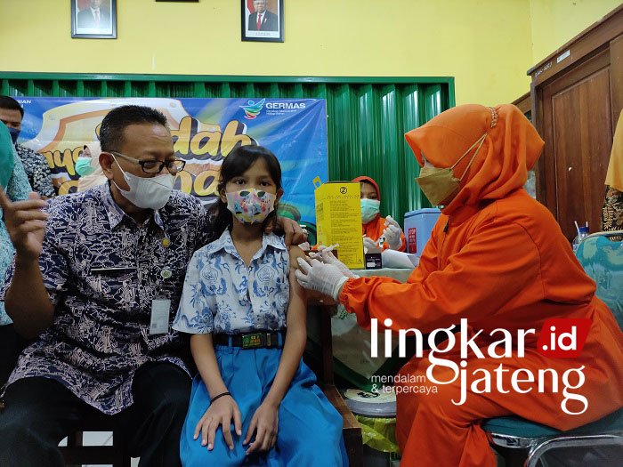 PATUH: Seorang siswi tampak tenang saat menerima suntik vaksin Covid-19 di sekolahnya, baru-baru ini. (Nisa Hafizhotus Syarifa/Lingkarjateng.id)