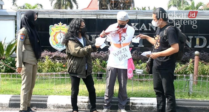 ILUSTRASI: Aksi teatrikal menampilkan seorang wartawan dalam kondisi terikat kebebasannya karena diberikan amplop untuk membungkam isu yang terjadi.