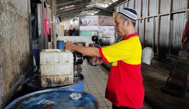 MENJUAL: Pedagang Pasar Bitingan saat memproses minyak curah untuk dijual. (Alifia Elsa Maulida/Lingkarjateng.id)