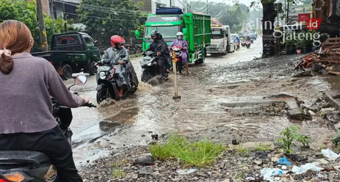 TERGENANG: Pengendara saat melintas jalan yang tergenang akibat perbaikan saluran air yang mangkrak.