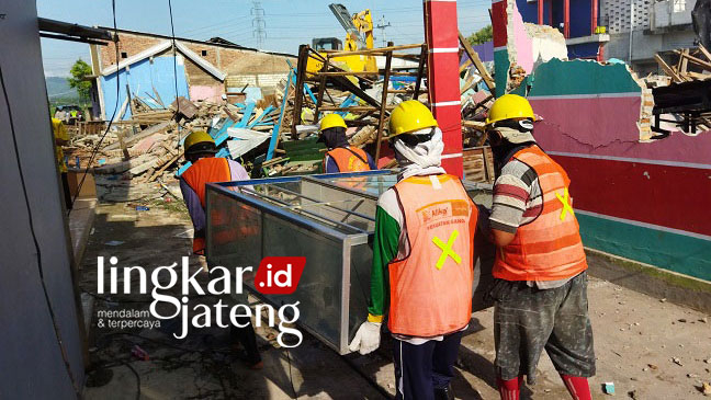 DIBONGKAR: Petugas berusaha mengamankan sejumlah perabot rumah tangga warga di Kawasan Lorong Indah Pati, sebelum menghancurkan rumah mereka dengan alat berat, kemarin (3/2). (Aziz Afifi/Lingkarjateng.id)