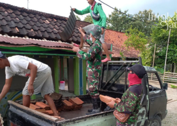 MEMPERBAIKI: Anggota TNI dan warga sedang memperbaiki pos kamling di Pandanharum, Senin (21/3). (Muhamad Ansori/Lingkarjateng.id)