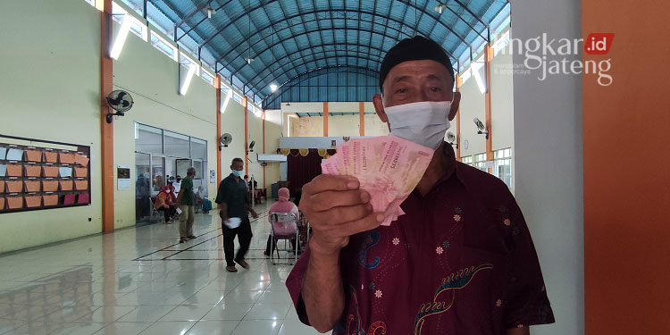 Cara Cek Penerima BLT Minyak Goreng Rp 300.000 25 SENANG: Seorang warga sedang menunjukkan BLT minyak goreng dan BPNT yang diambil di Balai Desa Jurang, Kecamatan Gebog, Kudus. (Nisa Hafizhotus Syarifa/Lingkarjateng.id)