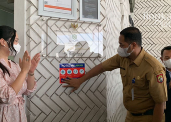 MEMASANG: Plt Kadinkes Kendal, Parno memasang label stiker di salah satu hotel Kendal untuk menunjukkan hotel tersebut aman dan sehat karena karyawan sudah vaksin booster. (Unggul Priambodo/Lingkarjateng.id)