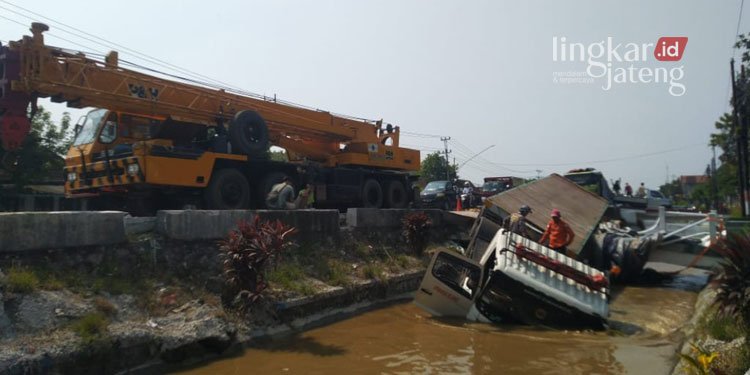NYUNGSEP: Truk trailer bermuatan pakan ternak tercebur di Sungai Pantura Karangsuno Kendal, Rabu (13/4). (Unggul Priambodo/Lingkarjateng.id)