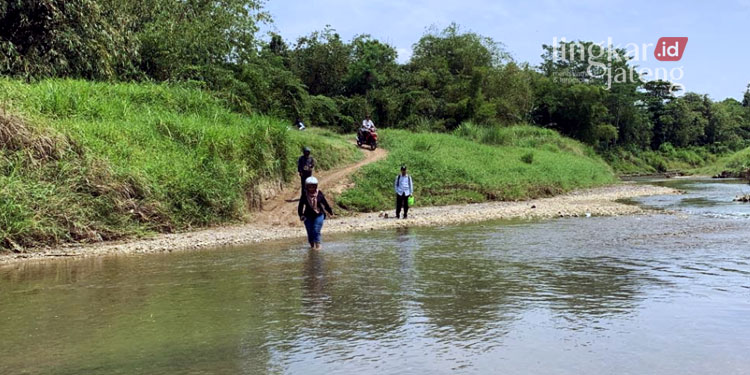 MENYEBRANG: Sejumlah warga Dusun Tapak Timur, Desa Kedunggading Kecamatan Ringinarum, Kabupaten Kendal harus menyebrang sungai menuju Balai Desa setempat. (Arvian Maulana/Lingkarjateng.id)