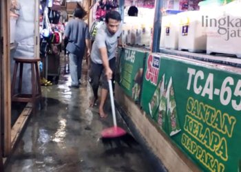 MEMBERSIHKAN: Salah satu pedagang Pasar Induk Purwodadi membersihkan air banjir yang menggenangi kios akibat atap bocor pada Kamis, 3 November 2022. (Muhamad Ansori/Lingkarjateng.id)