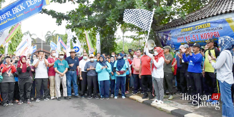 SIMBOLIS: Bupati Demak Eisti’anah (kerudung merah, baju putih, pegang bendera) mengibarkan bendera start tanda dimulainya acara jalan sehat dalam rangka HUT ke-51 Korpri, Jumat (18/11).