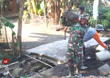 KERJA BAKTI: Anggota Koramil 01/Kota Kodim 0716/Demak Sertu Choerul H Babinsa Desa Karangmlati bersama warga melaksanakan pengecoran jalan penghubung antar desa, pada Senin, 26 Desember 2022. (Tomi Budianto/Lingkarjateng.id)