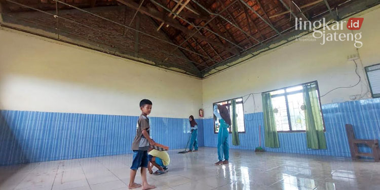 GOTONG ROYONG: Guru dan murid SD 3 Glagahwaru, Kecamatan Undaan, Kabupaten Kudus membersihkan material plafon yang runtuh diterjang angin kencang. (Ihza Fajar/Lingkarjateng.id)