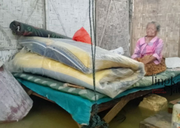 DIKEPUNG BANJIR: Seorang janda memilih tetap tinggal di rumah meski sudah tergenang banjir selama tiga hari. (Arif Febriyanto/Lingkarjateng.id)