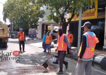 BEKERJA: Sejumlah pekerja sedang melakukan perbaikan jalan Jalan Loekmono Hadi, Kabupaten Kudus belum lama ini. (Nisa Hafizhotus S/Lingkarjateng.id)