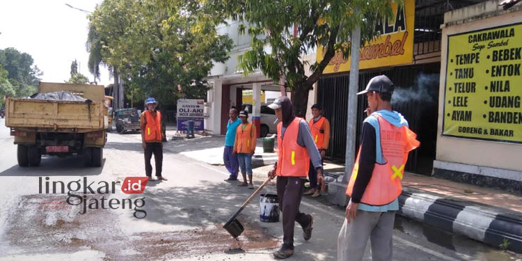 BEKERJA: Sejumlah pekerja sedang melakukan perbaikan jalan Jalan Loekmono Hadi, Kabupaten Kudus belum lama ini. (Nisa Hafizhotus S/Lingkarjateng.id)