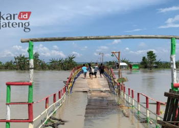 TERENDAM BANJIR: Jembatan Apung yang menghubungkan antara Desa Sambung, Kecamatan Gajah, Kabupaten Demak dan Desa Sambung, Kecamatan Undaan, Kabupaten Kudus ditutup sementara. (Muhammad Burhanuddin Aslam/Lingkarjateng.id)