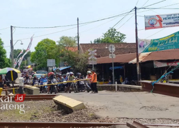 MENERTIBKAN: Petugas jaga saat menertibkan palang pintu perlintasan kereta api di Desa Nawangsari, Kecamatan Weleri, Kabupaten Kendal. (Arvian Maulana/Lingkarjateng.id)