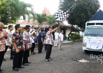 SIMBOLIS: Pj Bupati Pati, Henggar Budi Anggoro (pegang bendera) menghadiri Pelepasan Penyaluran Cadangan Beras Pemerintah untuk Bantuan Pangan 2023 di Gudang Bulog Sukokulon, Kecamatan Margorejo, Kabupaten Pati pada Selasa, 11 April 2023. (Dok. Official Website Pemkab Pati/Lingkarjateng.id)
