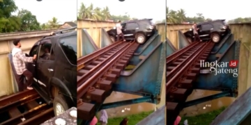 TERJEBAK: Sebuah mobil Fortuner nyungsep di jembatan rel kereta api atau KA di Sumpiuh, Kabupaten Banyumas pada Rabu, 19 April 2023. (Istimewa/Lingkarjateng.id)