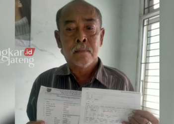 TUNJUKKAN BUKTI: Pedagang yang punya lapak di sebelah utara Pasar Rembang, Rum Basuki (65), menunjukkan surat perizinan berusaha yang diurus melalui sistem OSS. (R.Teguh Wibowo/Lingkarjateng.id)
