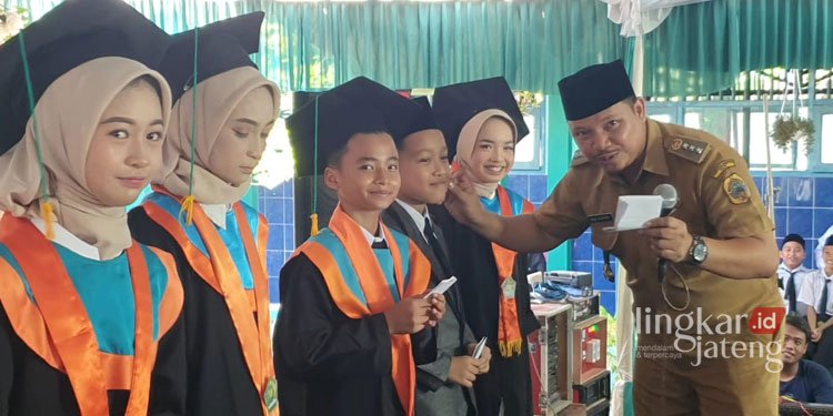 BERI PENGHARGAAN: Camat Dukuhseti, Agus Sunarko, S.STP., MSi. memberikan uang pembinaan kepada siswa MIN 2 Pati yang berprestasi. (Istimewa/Lingkarjateng.id)