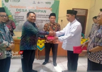 MNEYERAHKAN: Kepala Badan Kesbangpol Batang, Agung Wisnu Barata didamping Kepala Kemenag Batang Akhmad Farhan menyerahkan piagam pada Kades Kuripan, Kecamatan Subah. (Istimewa/Lingkarjateng.id)