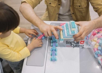 ILUSTRASI: Seorang anak usia dini bermain menyusun lego bersama orang tuanya. (Freepik/Lingkarjateng.id)