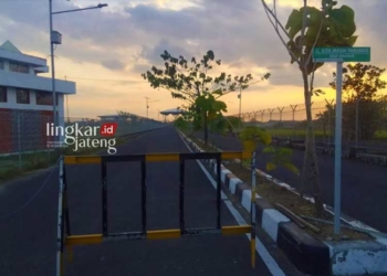DILARANG MASUK: Tampak jalan menuju Bandara Ngloram Kecamatan Cepu, Kabupaten Blora yang dipasang palang pembatas mencegah kendaraan masuk pada Jumat, 30 Juni 2023. (Hanafi/Lingkarjateng.id)