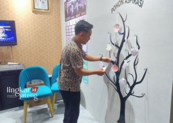 BERPARTISIPASI: Salah seorang warga sedang memasang gantungan kertas yang berisi usulan, kritikan, maupun aspirasi pada pohon aspirasi milik DPRD Kabupaten Kendal yang berada di salah satu stan Pekan Raya Kendal. (Unggul Priambodo/Lingkarjateng.id)