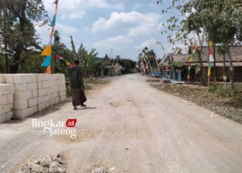 JALAN RUSAK: Seorang warga sedang melintas di Jalan Pelem-Jati yang saat ini kondisinya rusak. (Hanafi/Lingkarjateng.id)