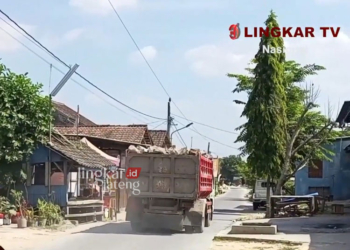 POLUSI: Truk pengangkut batu yang melewati pemukiman menyebabkan debu bertebaran di sekitar rumah warga. (Lingkar TV)