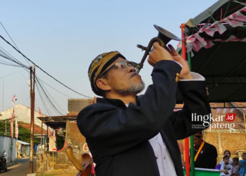 MELESTARIKAN: Ketua Pakasa Kudus Kanjeng Raden Arya (KRA) Panembahan Didik Gilingwesi Hadinagoro saat menggunankan Terompet Glongsor. (Nisa Hafizhotus Syarifa/Lingkarjateng.id)