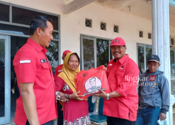 Ketua DPC PDI Perjuangan Akhmat Suyuti (memakai topi) secara simbolis memberikan paket sembako kepada warga yang mengikuti pengobatan gratis di Kendal. (Arvian Maulana/Lingkarjateng.id)