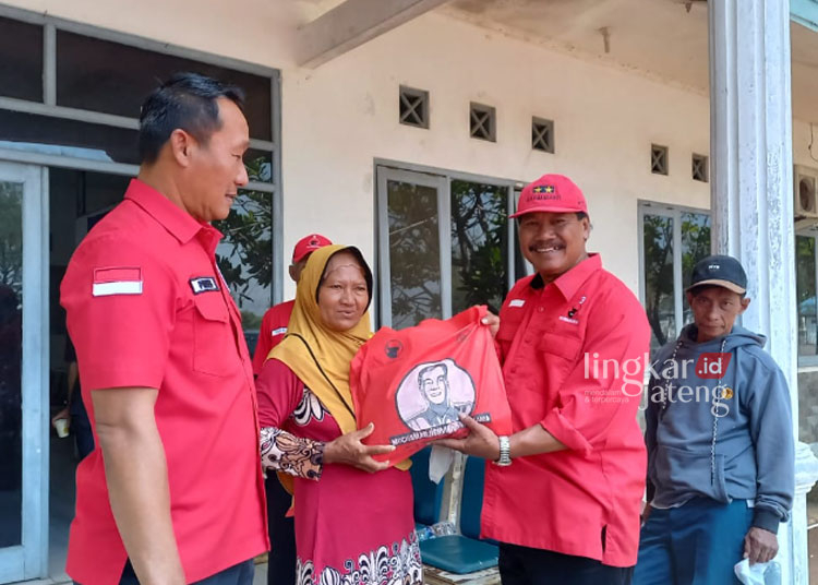 Jangkau Daerah Terpencil, Pengobatan Gratis Kapal Malahayati PDIP Bersandar di Kendal 25 Ketua DPC PDI Perjuangan Akhmat Suyuti (memakai topi) secara simbolis memberikan paket sembako kepada warga yang mengikuti pengobatan gratis di Kendal. (Arvian Maulana/Lingkarjateng.id)